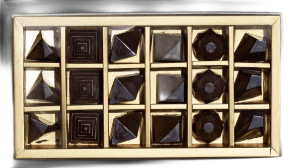 An open golden box of eighteen gem pralines